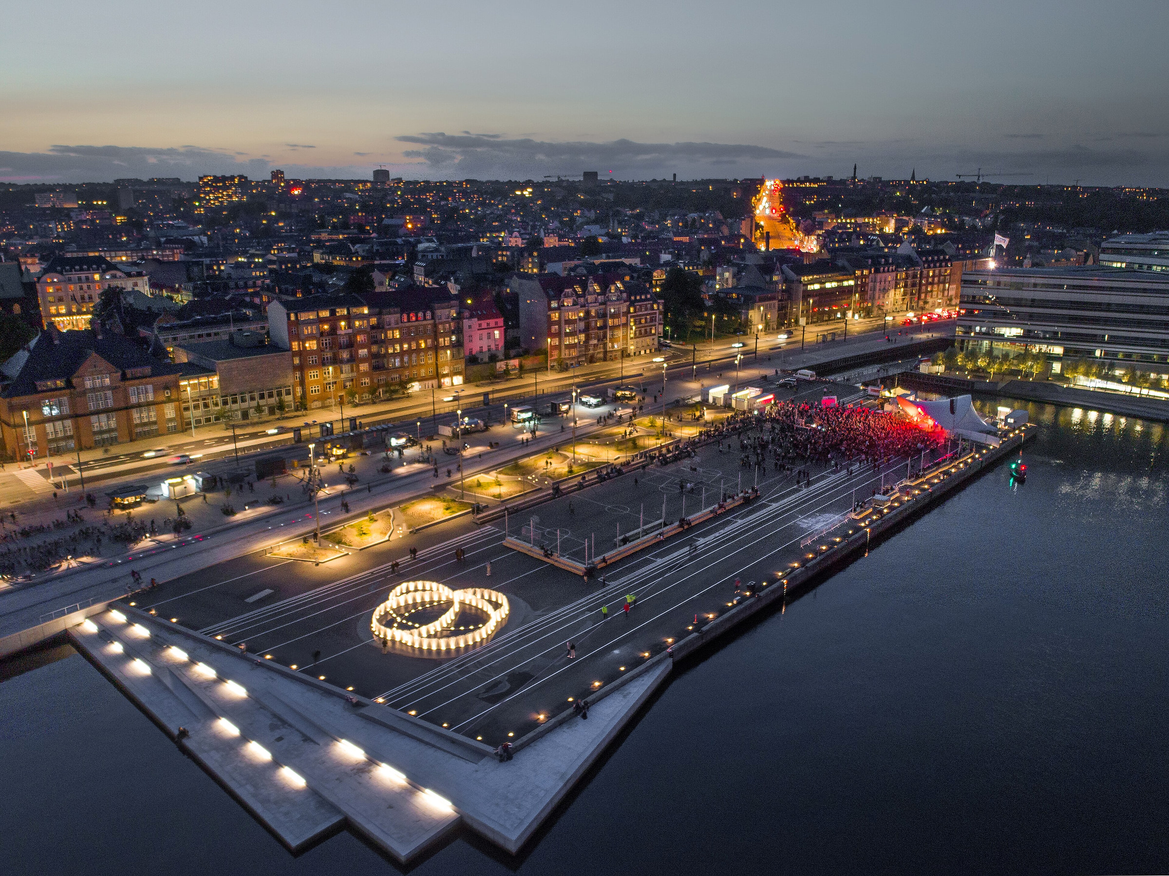 Aarhus om aftenen set fra oven med havnefronten og byens lys