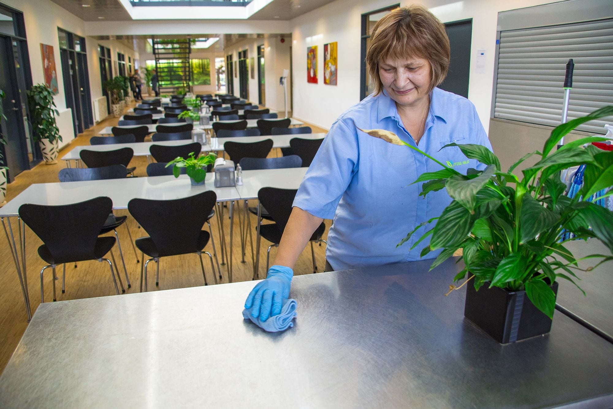 Medarbejder fra Jydsk Miljø tørrer borde af i en kantine